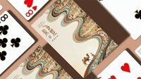 Beautiful for a Thousand Years playing cards with cream-colored backs, flowing multicolored ribbons, and intricate illustrated scenes