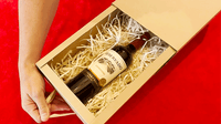 Wine bottle resting in shredded packing paper inside an open kraft Magic Box drawer.