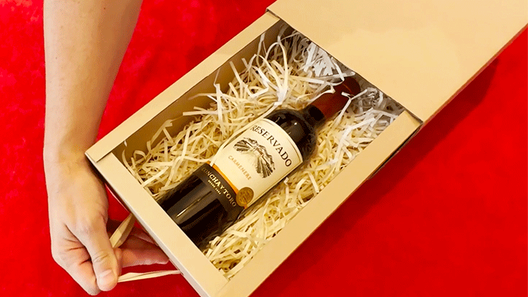 Wine bottle resting in shredded packing paper inside an open kraft Magic Box drawer.